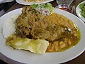 Kid stew accompanied by cooked yuccas, white rice, beans and Creole sauce