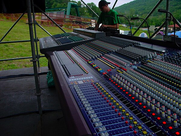 A Yamaha PM4000 and a Midas Heritage 3000 mixing console at the front of house position at an outdoor concert.