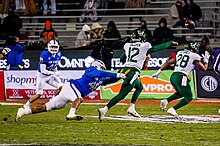 Baylor's Blake Shapen (12, white) throws a pass while being rushed by Air Force's Jayden Thiergood (48, blue) during the game U.S. Air Force Academy Armed Forces Bowl 2022 vs Baylor University (7570825).jpg