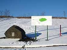 Khotiv hillfort. A stone with a metallic plaque, an information board and one of the red pillars which mark the reduced area of the archaeological monument (2016 version, shown in green on the board). Khotivs'ke gorodishche 0980-7006.jpg