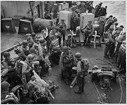 American soldiers, hardened and ready, lounge under full fighting equipment on the deck of a Coast Guard assault... - NARA - 196237.jpg