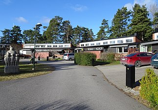 Före detta småskolelängan, nu ”Brf Tallringen”, till vänster står skulpturen "Sånglektionen".