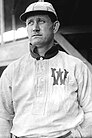 A man, wearing baseball cap and a white baseball uniform with the letter "W" on the left breast, 