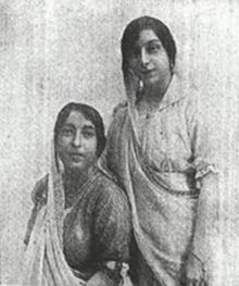 A black and white photograph of two women wearing saris