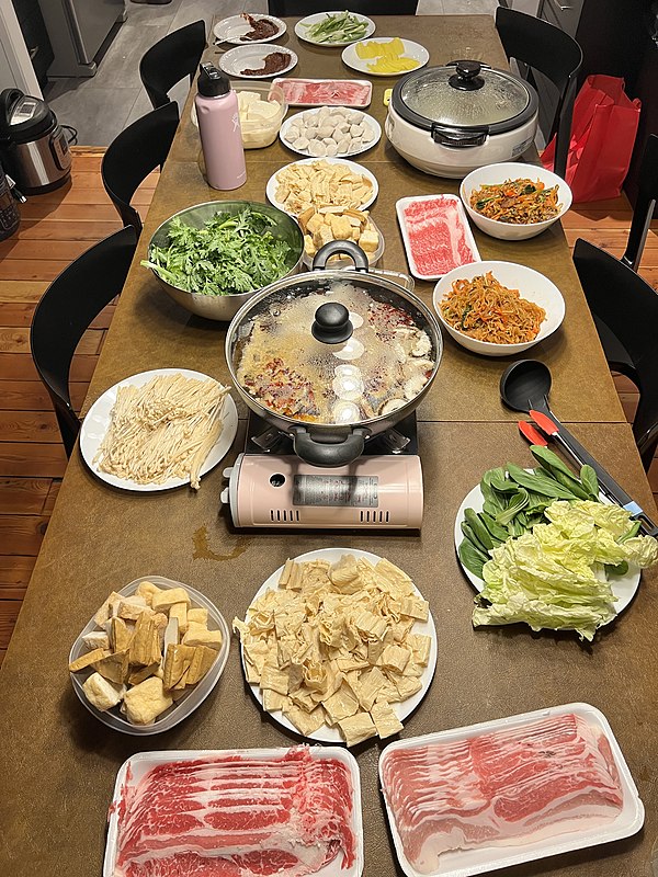 A presentation of raw foods ready to be cooked in a simmering broth