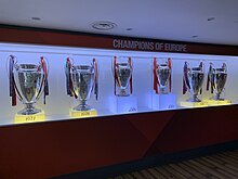 Six trophies inside a glass cabinet. The trophies have ribbons on them and there is memorabilia next to them