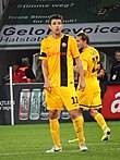 Joueur de football avec un maillot jaune barré d'une bande noire.