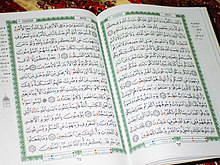 Photographie d'un Coran moderne ouvert sur un pupitre.