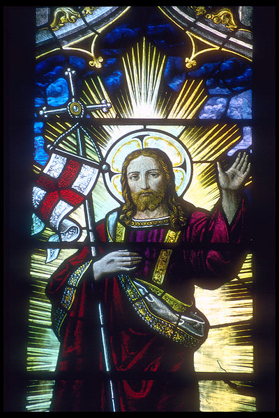 Jesus supporting an English flag and staff in the crook of his right arm depicted in a stained glass window in Rochester Cathedral in Rochester, Kent,