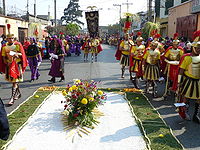 Jesus Nazareno de San Jose procession in Guatemala City which traditionally goes on Palm Sunday. Notice both the Catholic and the mayan insignia: Roman pendants and uniforms on one hand, and a carpet made of flowers on the other. Romanossanjose.JPG