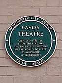 City of Westminster green plaque at the Savoy Theatre, the first public building in the world to be lit entirely by electricity when it was fitted with the incandescent light bulb developed by Sir Joseph Swan in 1881.[45]