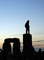 Man standing on one of the Sarsen stones shortly before sunrise