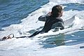 A surfer paddling.