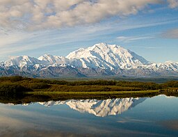 Denali från Wonder Lake norr om berget. Sjöns höjdläge på 610 m ö.h. med platån intill utgör bergets höjdskillnad mellan dal och topp till över 5 500 m, vilket anses vara världens största på land (cirka 2 000 m högre stigning än Mount Everest).