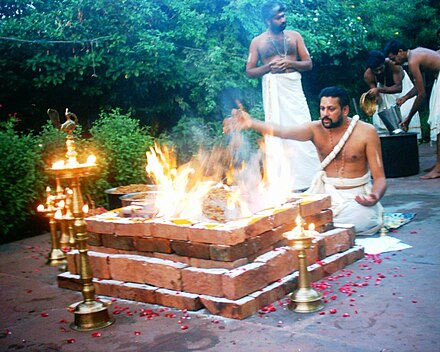 Yajurveda text describes formula and mantras to be uttered during sacrificial fire (yajna) rituals, shown. Offerings are typically ghee (clarified butter), grains, aromatic seeds, and cow milk.