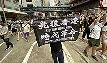 On 1 July 2020, the day after implementation of the security law, tens of thousands of Hong Kong people gathered on the streets in Causeway Bay to march. On 2 July, the Hong Kong government declared the 'Liberate Hong Kong, revolution of our time' slogan depicted on a banner here - "the most resonant slogan of its protest movement" - to be subversive and in violation of the law. 1 july 2020 implementation Hong Kong Law streets in Causeway Bay.jpg