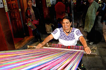 Weaving narrow cloth on a back-strap loom. A lone weaver without a flying shuttle must be able to span the cloth they are weaving with their arms. BackstrapUruapan (darken background).jpg