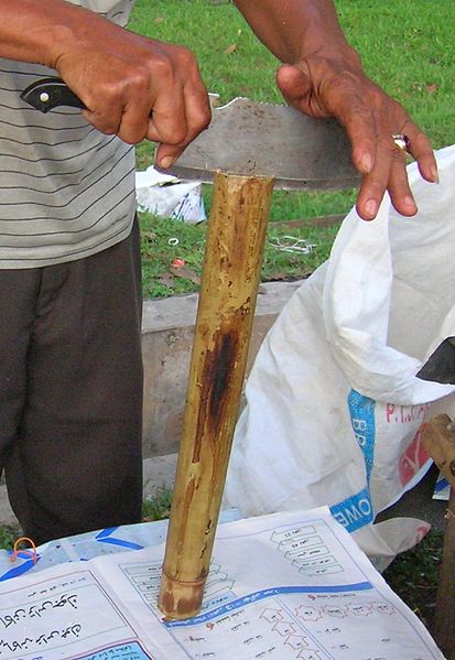 Cutting the hollowed bamboo to retrieve the lemang inside
