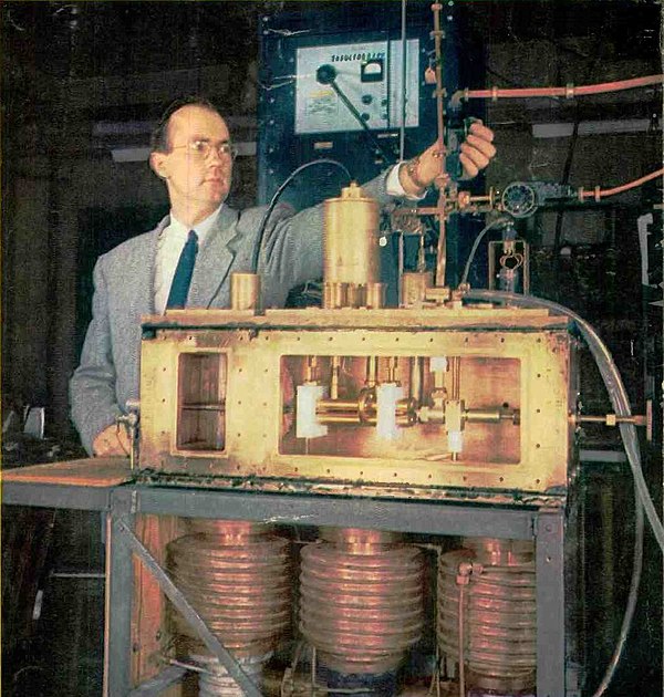 The first prototype ammonia maser in front of its inventor Charles H. Townes. The ammonia nozzle is at left in the box, the four brass rods at center 