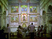 A string concert performed by people in white robes sitting in front of the altar.