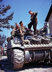 A Canadian tank crew during the Battle of Normandy. The crew member in the centre is wearing a black beret, headgear that was adopted by Canadian armoured regiments in 1937. Crew of a Sherman-tank south of Vaucelles.jpg