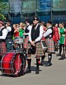 A drummer of the International Celtic Pipes and Drums with a marching bass drum. (2019).