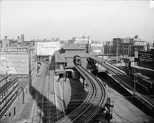 Looking north at the former elevated station's northbound platforms in 1904, with the streetcar loops on each side; an elevated train can be seen in the station, while a streetcar is visible using the right-hand loop and another is using the street-level tracks beneath the left-hand loop. Dudley northbound platforms.jpg