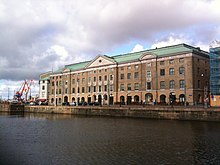 Photo contemporaine de l'ancien bâtiment de la Compagnie suédoise des Indes orientales à Göteborg. Il s'agit d'un grand bâtiment de briques rouges surmonté d'un toit en cuivre.