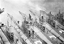 L-class submarines USS L-3, USS L-11, USS L-10, USS L-4, and USS L-9 alongside their submarine tender in British waters in 1918. The "A" (for "American") was added to avoid confusion with British L-class submarines. NH-60252 L-class submarines in British water, 1918.jpg