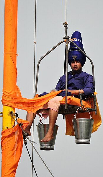 A Nihang Singh changing cloth of Nishan Sahib, Gurdwara Singh Shaheedan, Sohana, Mohali, Punjab, India