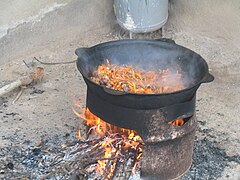 Plov (pilaf) being made in a kazan suspended above a fire using a metal frame.