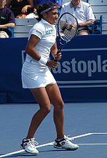 A lady facing forward holding a tennis racket out in front of her body