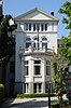 Villa. Gepleisterde gevel met getoogde en rechthoekige vensters, driezijdig uitgebouwde erker met balconhek en bekronend fronton