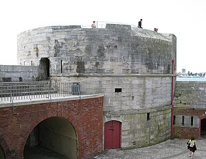 A front facing view of Portsmouth's Round Tower, which once guarded the entrance to Portsmouth Harbour. The Round Tower itself is made of stone and has a large circular base.