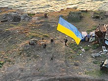 Vlajka vejúca pri brehu ostrova, rôzne trosky v okolí