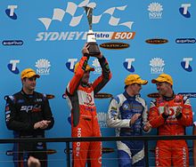 Jamie Whincup (holding trophy) celebrates his 2011 championship victory, while the podium finishers from the Sunday race watch on. 2011 V8s top 4.JPG