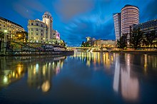 Un canal bastante ancho, con un edificio algo antiguo por un lado y un edificio algo moderno por el otro, ambos con una torre y un edificio.