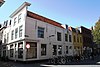 Huis met rechte gepleisterde gevel. Dakkapel. Op de hoek met Kerkstraat 1: moderne winkelpui. Kelderlichten