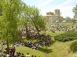 Grand groupe de personnes pique-niquant dans un décor de parc, avec une église en arrière-plan