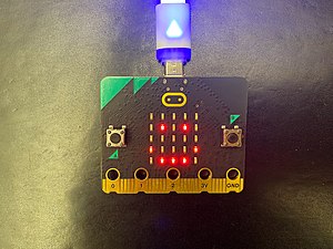 Ein BBC micro:bit, bei dem die interne Anzeige in Form eines Smiley leuchtet