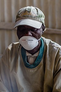 Paul Were Abura, a bone artist at Victorious Bones Craft wearing a disposable dust mask to protect him from the dust produced while softening bones to make fine jewellery.