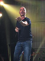 Seorang pria yang mengenakan celana jeans dan jaket kulit muncul di atas panggung