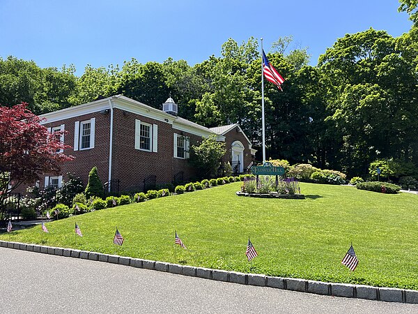 Flower Hill Village Hall in 2023, with flags on the lawn to celebrate Memorial Day.