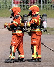 Elastomeric masks linked to backpack air tanks: self-contained breathing apparatus, worn by firefighters advancing with a firehose. Interschutz 2010 Brandbekampfung (1).jpg