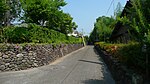 Kleine Straße, gesäumt von niedrigen Steinmauern.