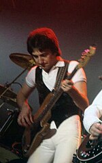 Deacon on stage at the New Haven Coliseum, Connecticut, US, in 1977 John Deacon (1977).jpg