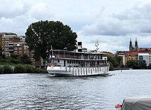 M/S Juno i Liljeholmsviken, sedd akterifrån. I fonden skymtar Högalidskyrkan på Södermalm, 2023.