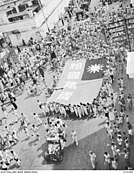 Chinese community holding preliminary celebrations through the city streets, with liberation banners