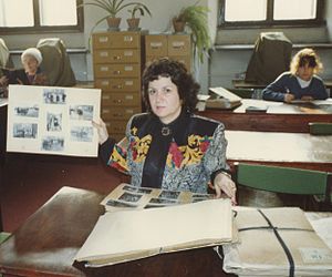 Miriam Weiner in the State Archive of Krakow (Poland) in the Reading Room looking at deportation photos taken during the Holocaust. Photo taken July 1990 Miriam Weiner in the State Archive of Krakow (Poland) in the Reading Room looking at deportation photos taken during the Holocaust, July 1990.jpg