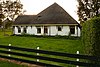 Mooi gelegen stolpboerderij met kort voorhuis en lage (moderne) uitbouw aan aangrenzende zijde. Vensters met roeden